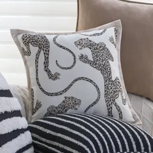 00-13 Kissenhülle mit Leopardenmotiv auf Weiß und beigem Rand auf einem Sofa