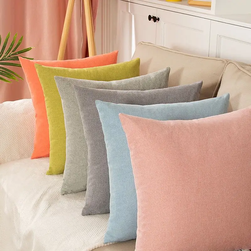 Mehrere einfarbige Kissen in Orange, Grün, Grau, Blau und Rosa nebeneinander