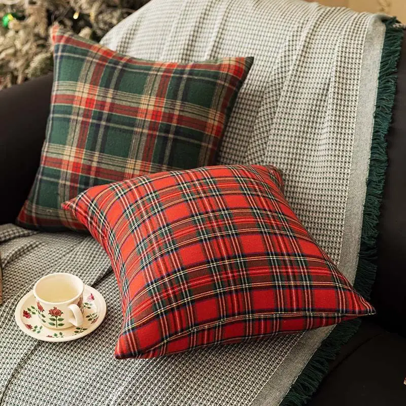 Zwei Kissenhüllen mit rotem und grünem Schottenkaro auf einem Sofa mit Decke