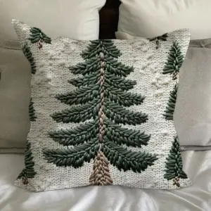 Kissenbezug mit grünem Tannenbaum-Motiv auf cremefarbenem Grund auf einem Bett