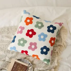 Weißes Kissen mit bunten, plastisch wirkenden Blumen auf einem Bett