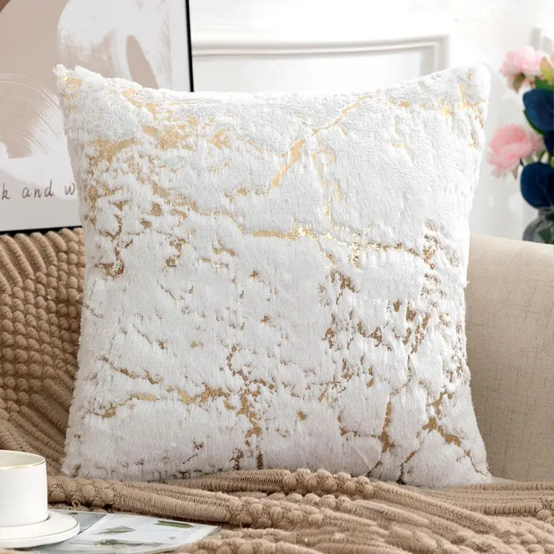 Weißes flauschiges Kissen mit goldenen Marmorlinien auf einem Sofa