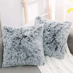 Zwei graue, langhaarig zottelige Kissenbezüge in Fell-Optik auf einem Sofa