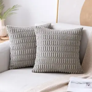 00-7 Zwei graue Kissen mit Streifen- und Noppenstruktur auf einem hellen Sofa
