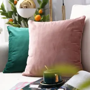 Rosa und grüne Kissenhüllen vor einem grauen Sofa mit Zeitschrift