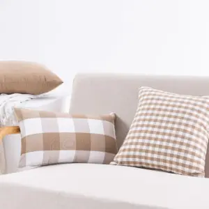 Beige-weiße Kissen mit Karo- und Streifenmuster auf einem Sofa
