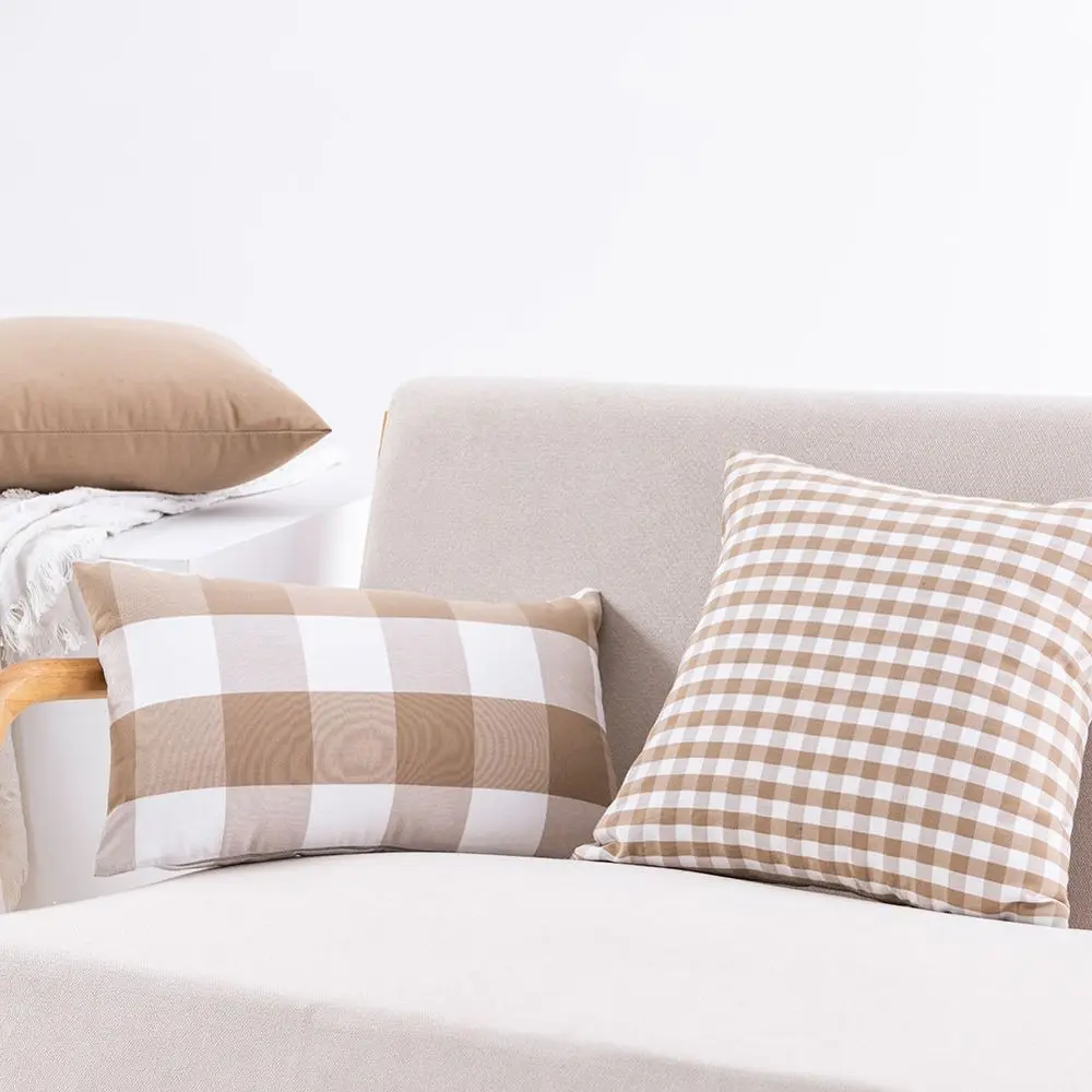 Beige-weiße Kissen mit Karo- und Streifenmuster auf einem Sofa