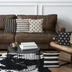 Schwarz-beige Kissen mit Streifen- und Kreuzmuster vor einem braunen Sofa