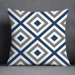 Kissen mit blau-grauem Rauten- und Zickzackmuster vor einem grauen Sofa