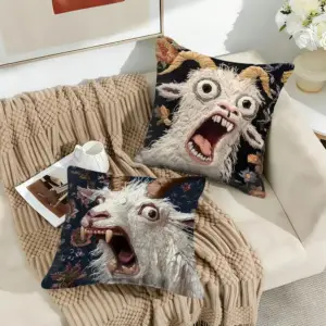 Zwei Kissenhüllen mit schreiender Ziege vor Blumenmuster auf einem Sofa
