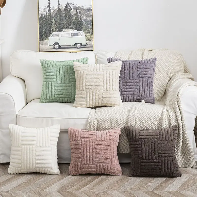 Sechs Kissenhüllen mit erhabenem Muster in Grün, Creme, Lila, Rosa und Braun auf einem hellen Sofa